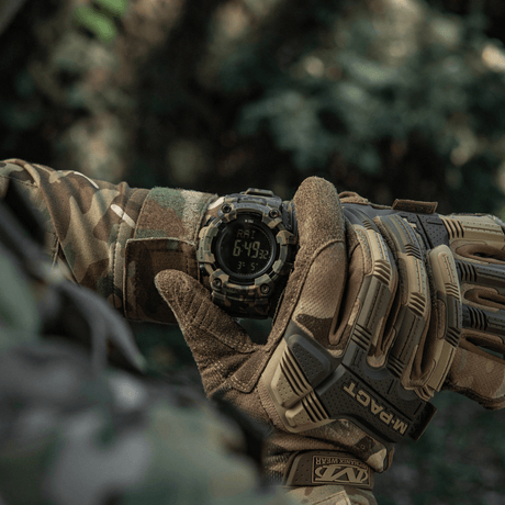 M-Tac Tactical Ur 2037 i brug i naturen, vises på håndleddet af person i camouflage-tøj, viser LED-baggrundsbelyst skærm og funktioner.