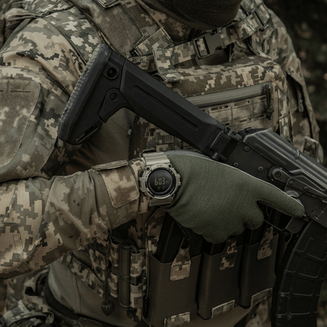 Person iført camouflagetøj bærer M-Tac Tactical Ur med Kompas 2233 i en militær setting.