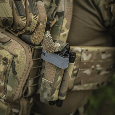 M‑Tac Tourniquet Pouch Elastic Gen.5 fastgjort til taktisk udstyr i camo-design, med en tourniquet sikkert opbevaret.