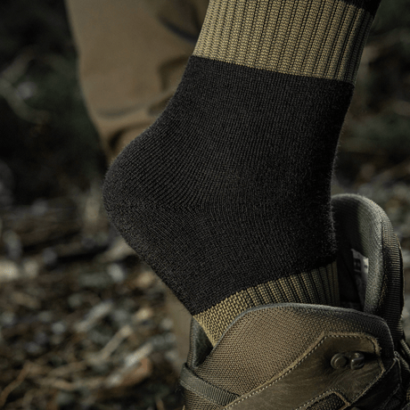 M-Tac Vinter Sokker med elastisk kant og anatomisk pasform for optimal komfort og varme under kolde forhold, set i en army-støvle.