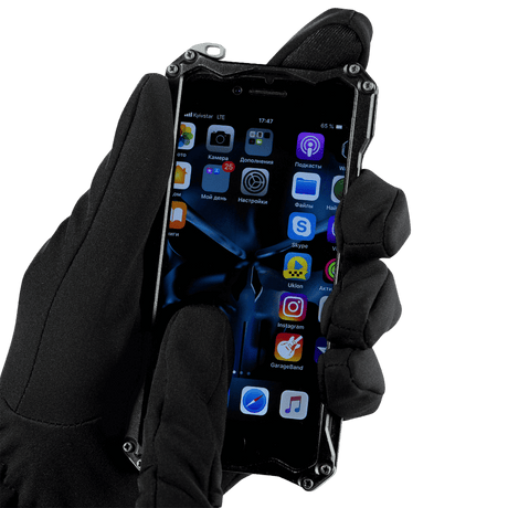 Person iført M-Tac Vinterhandsker Soft Shell bruger smartphone i koldt vejr for maksimal beskyttelse og komfort