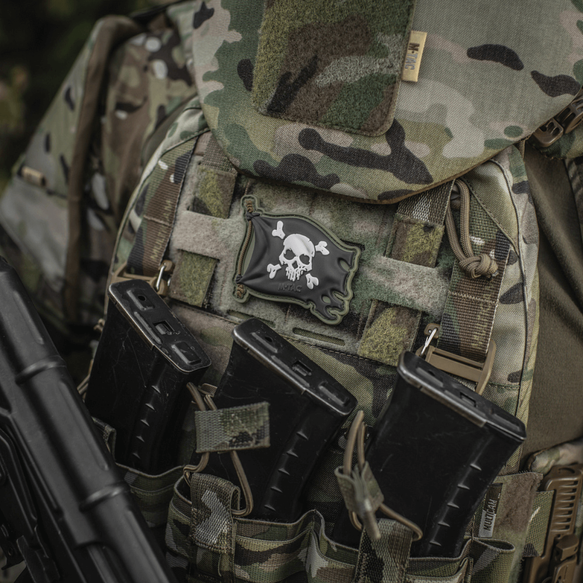 M-Tac Patch Jolly Roger PVC fastgjort på taktisk rygsæk med camouflage-mønster, symboliserer eventyrlyst og beslutsomhed.