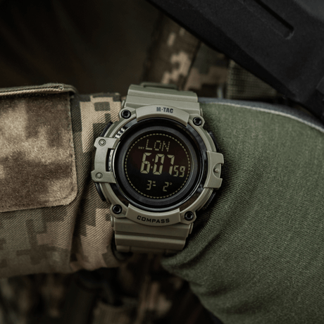 M-Tac Tactical Ur med Kompas 2233 båret af en person i camouflage, perfekt til outdoor aktiviteter med LED-belysning og stopur.