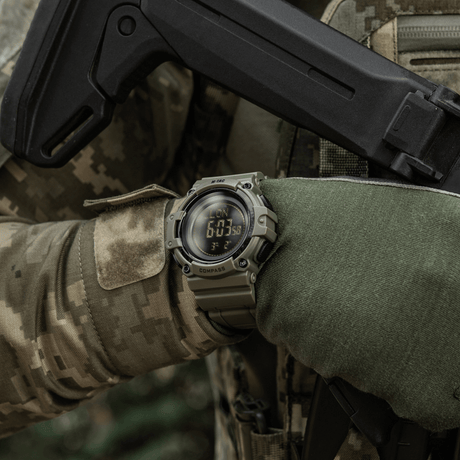 M-Tac Tactical Ur med Kompas 2233 i brug i outdoor-taktisk scenario, viser robusthed og funktionalitet med kompas og LED-baggrundsbelysning.