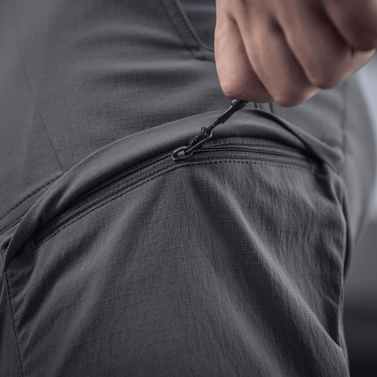 Nærbillede af lynlåsdetalje på M-Tac Bukser Sahara Flex Light, der fremhæver fleksibilitet og holdbarhed.