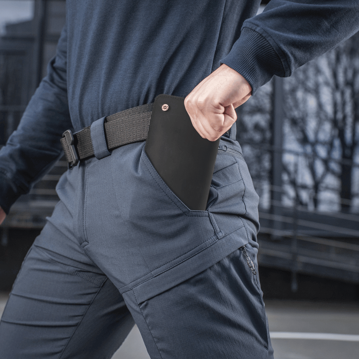 Person iført M-Tac Bukser Sahara Flex Light med en hånd i lommen udendørs.