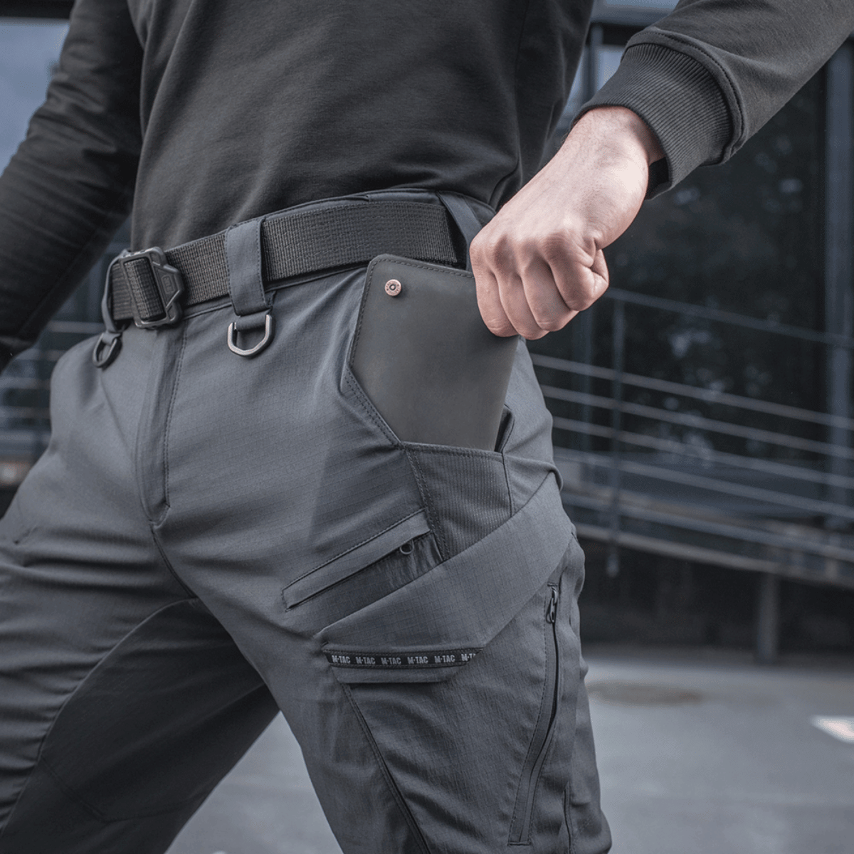 Mand iført M-Tac Bukser Aggressor Summer Flex, lavet af Rip-Stop nylonstof, ideelle til varmt vejr for taktisk komfort.