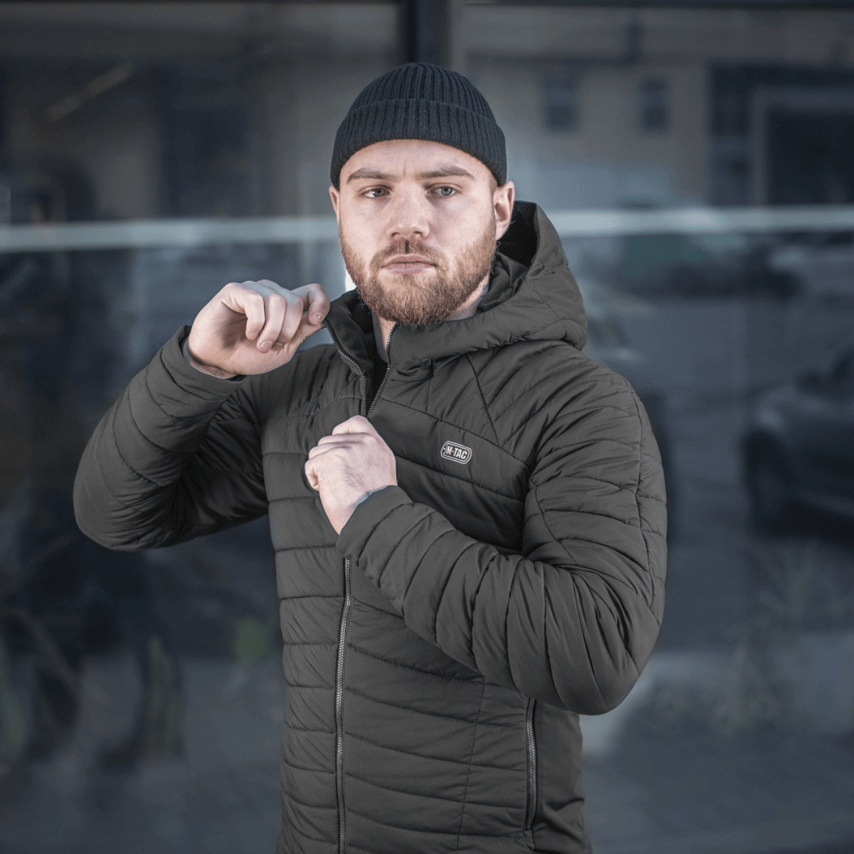 Mand iført M-Tac Jarl Jakke i sort, designet med åndbart og isolerende materiale til mellemsæsonen, perfekt til at beskytte mod kulde.