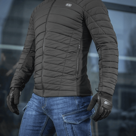 Person iført M-Tac Jarl Jakke i sort, står udenfor klar til koldt vejr, kombineret med jeans og handsker, teknologi og komfort.