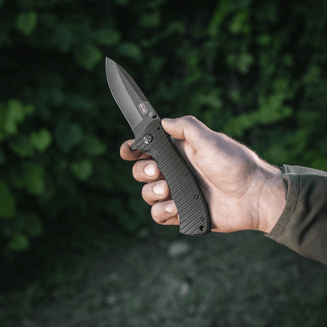 M-Tac Outdoor & Militær foldekniv - Type 7 med krom rustfrit stål klinge holdt i hånden, fremstillet til taktiske formål.