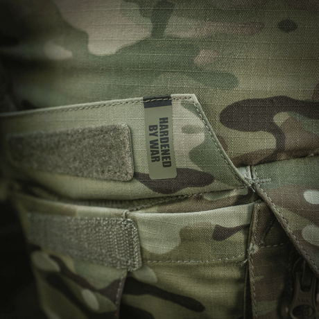 Detaljer af M-Tac Shorts STURM Gen.II Nyco Extreme med camouflagemønster og "Hardened by War" etiket, ideel til taktisk brug.