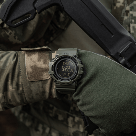 M-Tac Tactical Ur med Kompas 2233 båret af taktisk udstyr brugt af en person, ideelt til udendørs og taktisk brug, med LED-baggrundsbelysning.