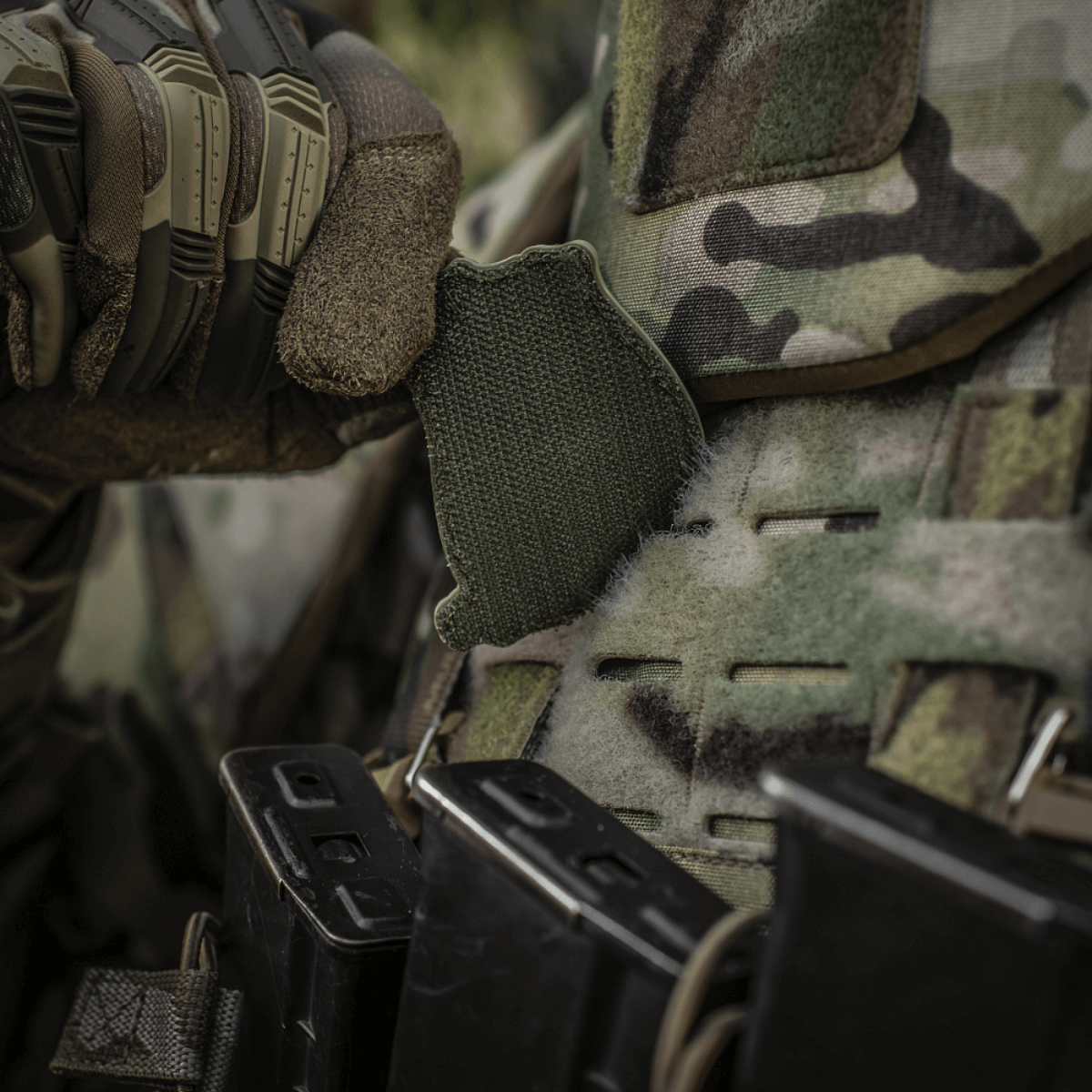 En soldat justerer en M-Tac Patch Jolly Roger PVC på sin camouflage-vest under taktisk træning udendørs.