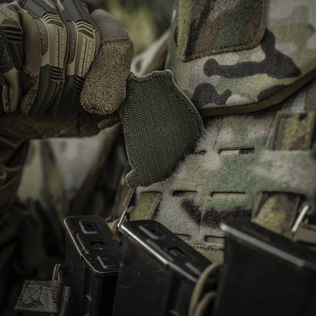 En soldat justerer en M-Tac Patch Jolly Roger PVC på sin camouflage-vest under taktisk træning udendørs.