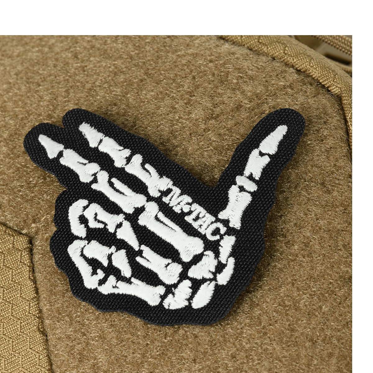 Patch med skeletmotiv på M-Tac Buckler Taske Elite Hex, i sort og hvid, fra M-TAC. Vist på en brun baggrund af Hex-Cordura materiale.