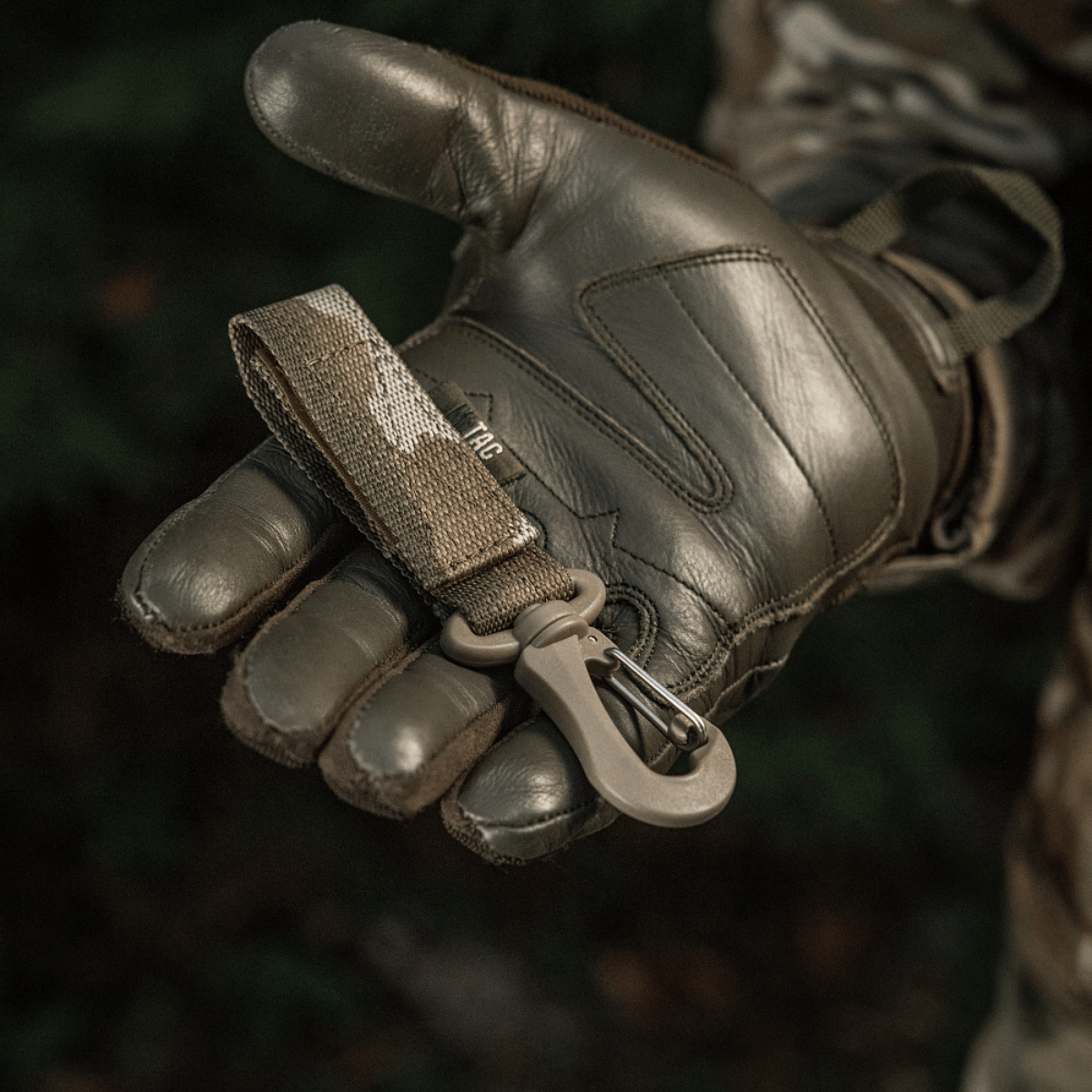 M-Tac Karabinhage Tilbehør siddende på militærhandske med MOLLE-system og Velcro-rem for sikker fastgørelse af udstyr.