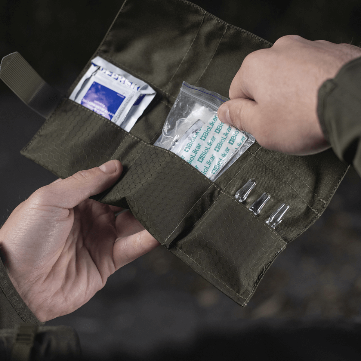 M-Tac City Med Pouch Hex åben og indeholdende førstehjælpsartikler, lavet af holdbart Hex Polyester med Velcro lukning.