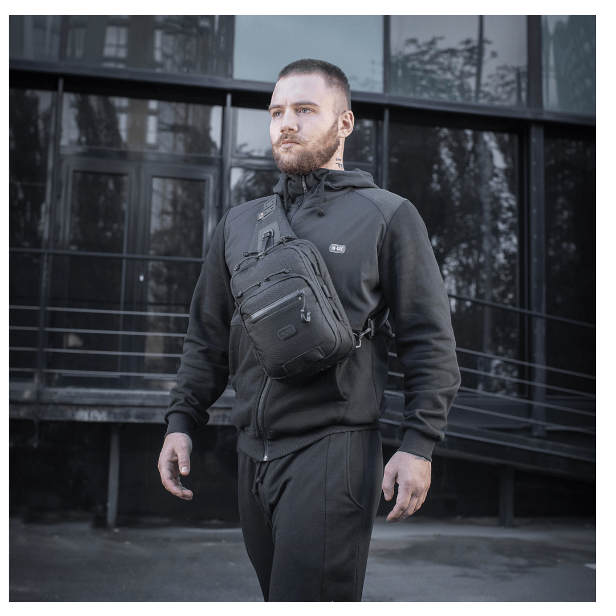 Mand bærer M-Tac Cross Taske Slim Elite Hex, en stilfuld og funktionel taske lavet af Cordura med YKK og Woojin tilbehør.