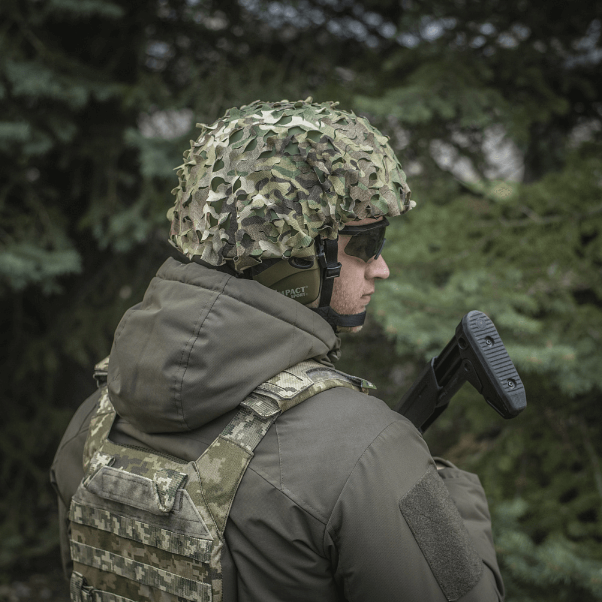 Soldat iført M‑Tac Vilha Hjelmdæksel Elite i Multicam skovkamouflage, designet til FAST hjelme, set fra siden.