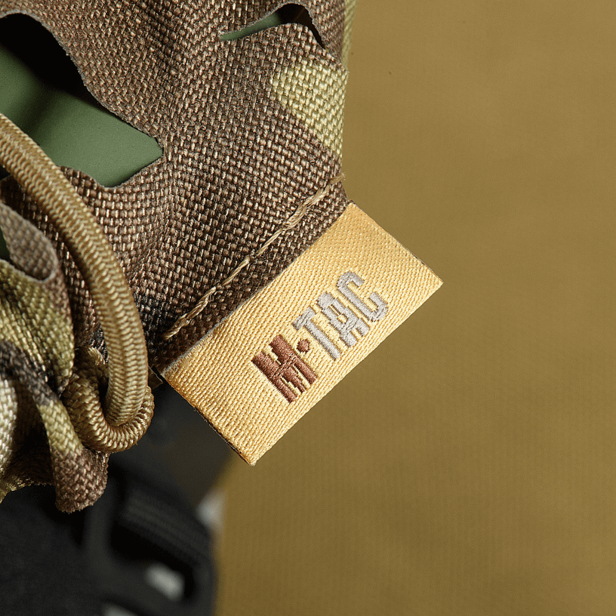 M‑Tac Vilha Hjelmdæksel Elite i Multicam camouflage med Cordura 500D og Laser Cut beslag, nærbillede af mærket.