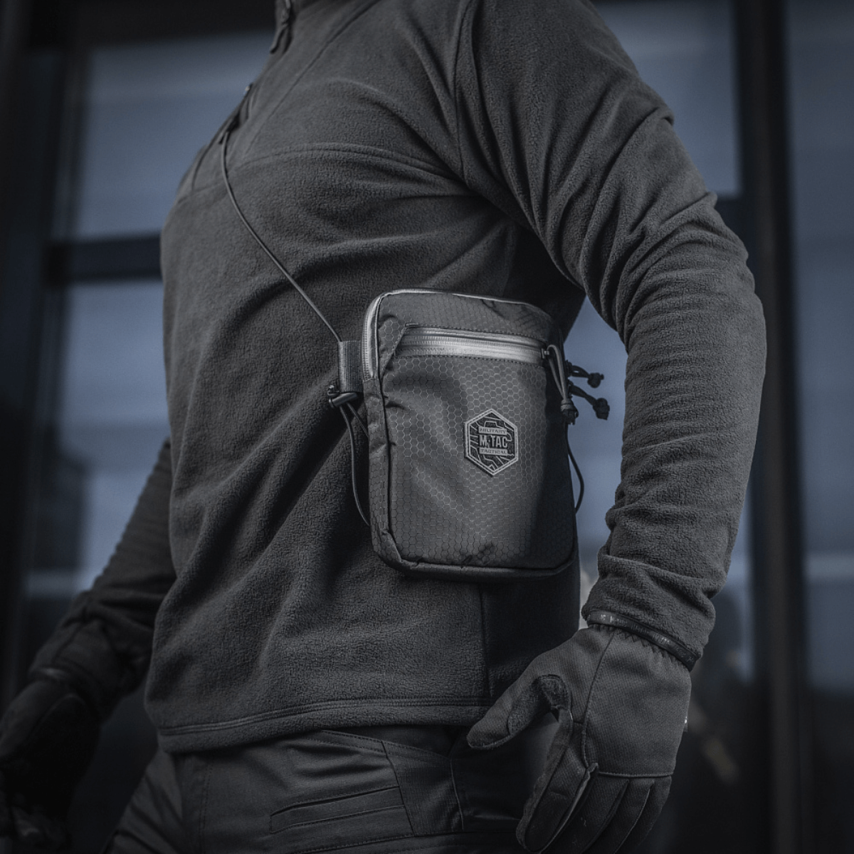 Person med M‑Tac Pocket Bag Elite HEX, en kompakt taske ideel til EDC-udstyr og nøgler, lavet af slidstærkt materiale med YKK lynlåse.