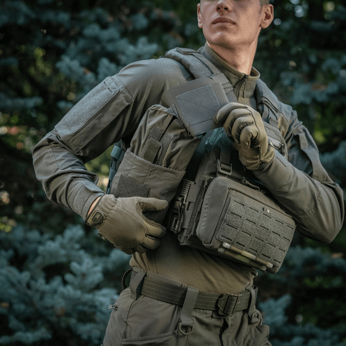 Person iført taktisk vest med M‑Tac Medic Pouch Vertical Large Elite i skovområdet.