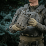 Soldat holder M‑Tac Medic Pouch Vertical Large Elite i et skovmiljø, demonstrerer taskens holdbarhed og design.