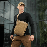 Mand bærer en M-Tac Tablet Bag Laser Cut Hex i sandfarve foran en moderne bygning.