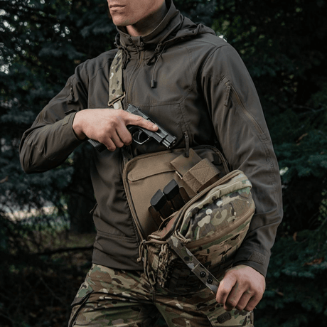 Mand med M-Tac Tablet Bag Laser Cut Hex i camouflage, viser skjult våbenopbevaring og hurtig adgang i tasken.