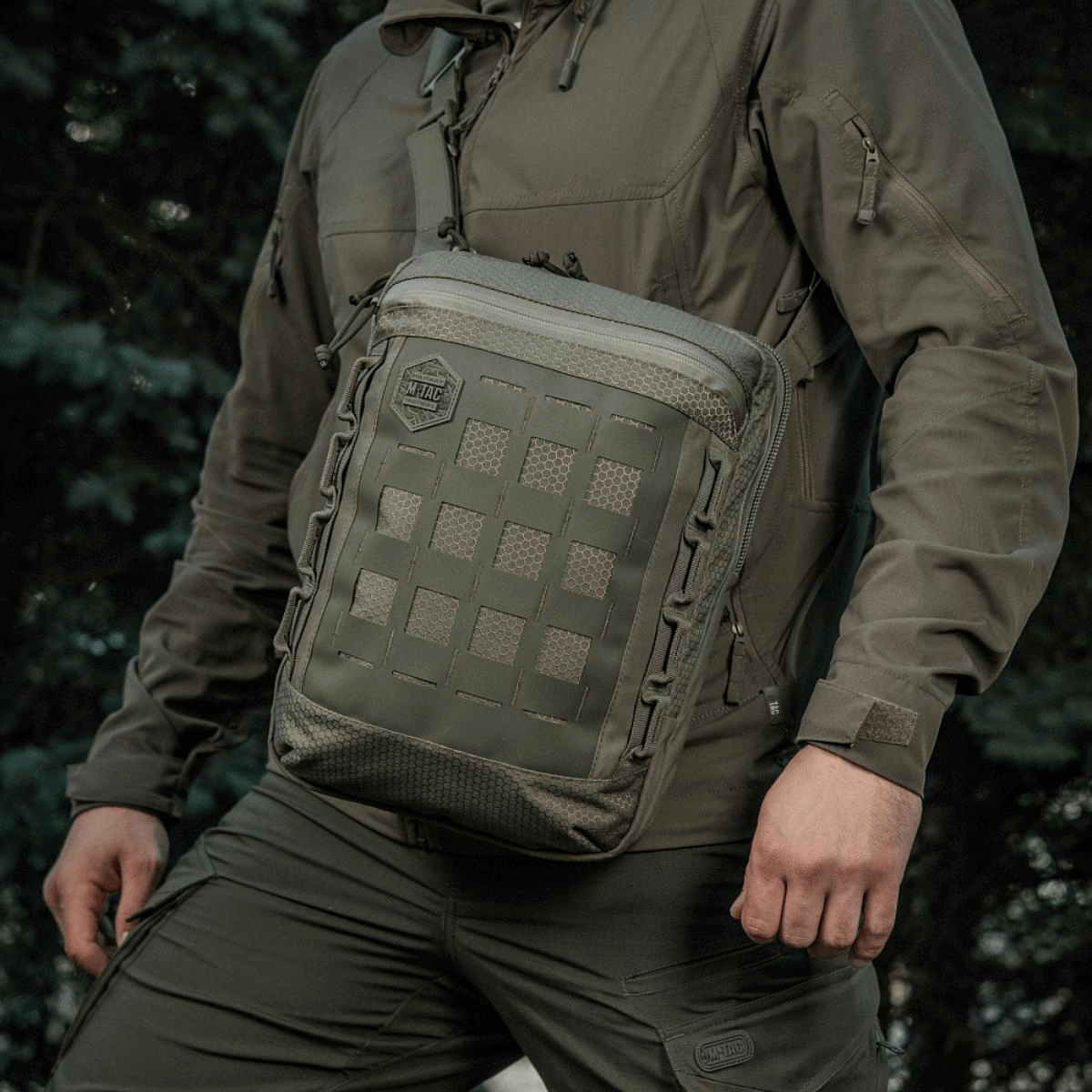 Person wearing the M-Tac Tablet Bag Laser Cut Hex with MOLLE panel outdoors