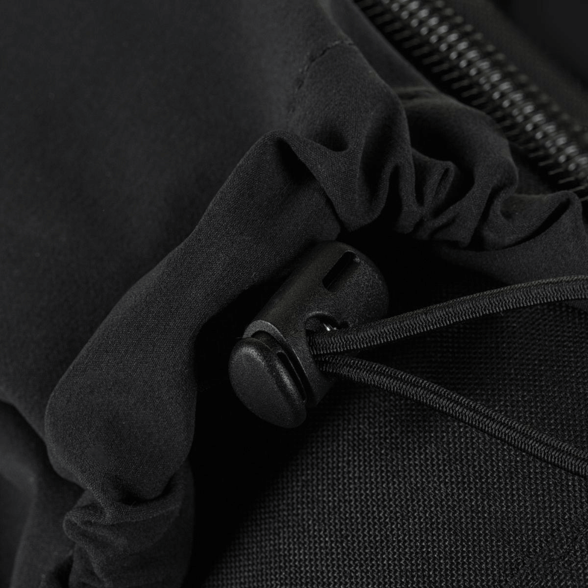 Nærbillede af en sort snøre og lynlås på tøjmateriale