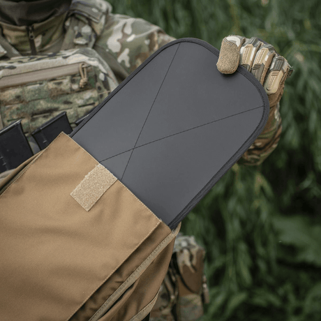 Soldat i camouflageuniform viser taktisk pladeholder med udtrukket beskyttelsesplade