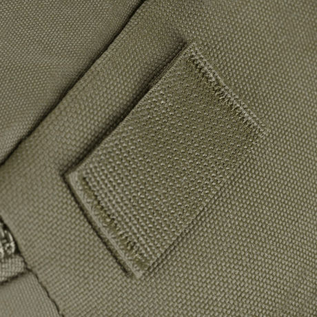 Detalje af olivengrøn tekstil med syning og lynlås på tættet hold