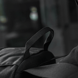 Sort rygsæk og strop i fokus med sløret baggrund