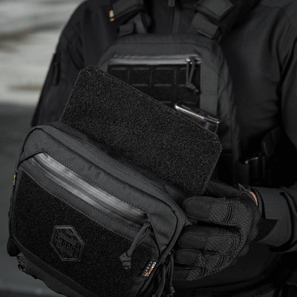 Person holder M-Tac Large Elite Gen.II Skuldertaske med taktisk udstyr og Velcro-panel, fremstillet af holdbart Cordura 500D materiale.