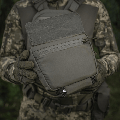 M-Tac Large Elite Gen.II Skuldertaske holdt af person i camouflage, fremstillet af Cordura 500D, perfekt til taktisk brug og udstyrstransport.
