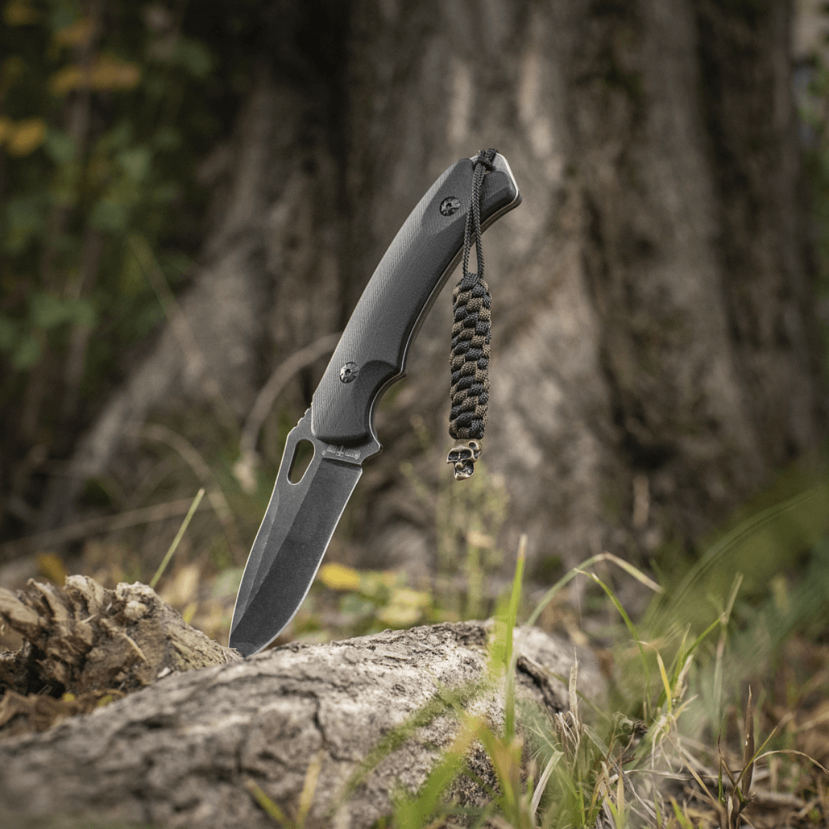 M-Tac Knife Lanyard Helix Skull paracord lanyard på lommekniv i skovmiljø for stil og funktion.