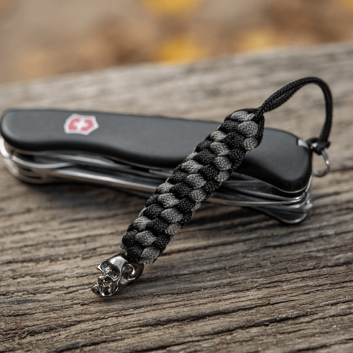 M-Tac Knife Lanyard Helix Skull vedhæftet til en lommekniv, der viser unik stil med flettet paracord og dødningehoveddetalje.