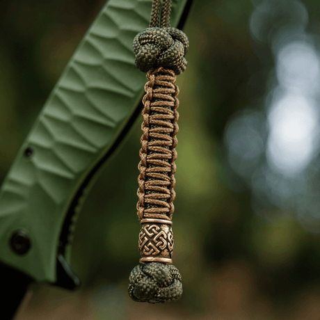 M-Tac Knife Lanyard Celtic i flettet paracord med dekorativt celtisk mønster vedhæftet til gribedelen af en kniv.