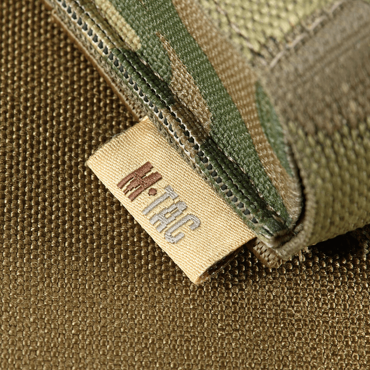 M-Tac Gasdåseholder Vertikal med MIL-SPEC strop og Woojin-lås, vist i nærbillede af mærkesyning i camouflage design.