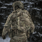 M-Tac Rygsæk Sturm Elite Gen.II i camouflagedesign med MOLLE system, set bagfra i skovmiljø med sne.