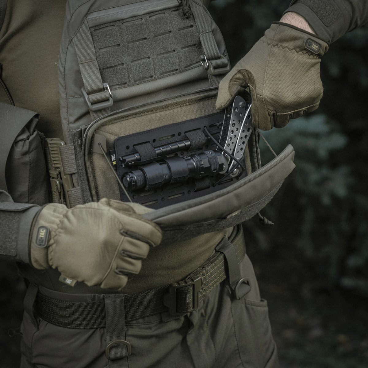 Person åbner M-Tac Admin Pouch Large Elite med taktisk udstyr, fremstillet af slidstærkt Cordura 500D, velegnet til udendørs brug.