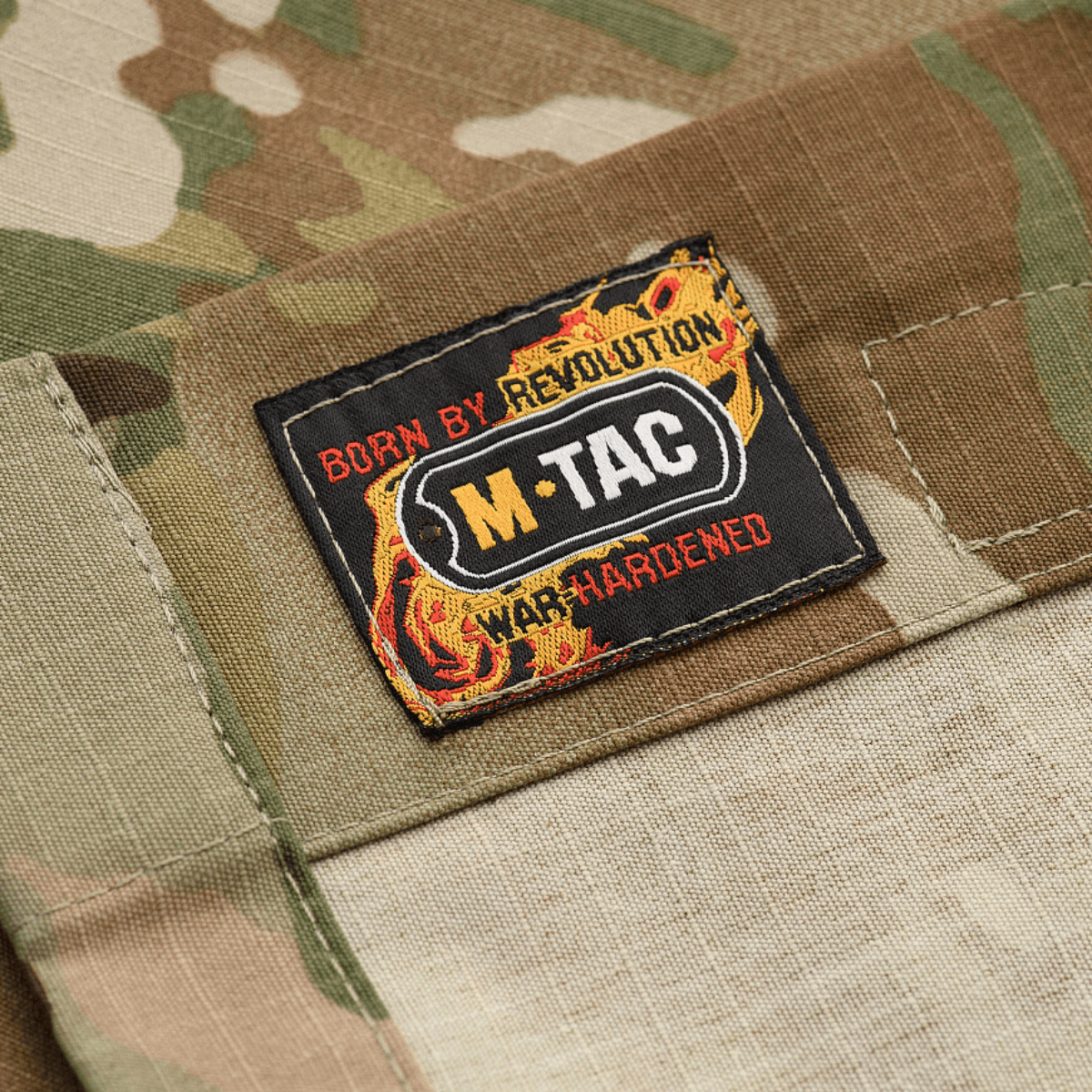 M-Tac Jakke Military Elite NYCO med original Crye Precision MultiCam stof, nærbillede af M-Tac mærke på camouflagejakke. Perfekt til feltdragt kombination.