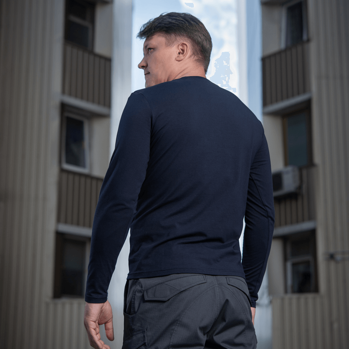 Mand i M-Tac Long-sleeve T-shirt 93/7 foran bygning, set bagfra