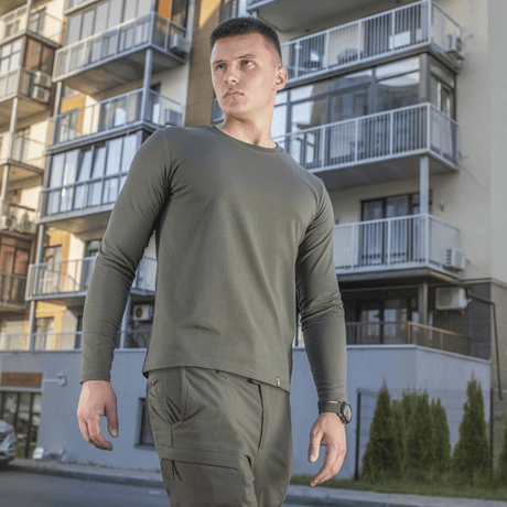 Mand iført M-Tac Long-sleeve T-shirt 93/7 foran moderne bygning