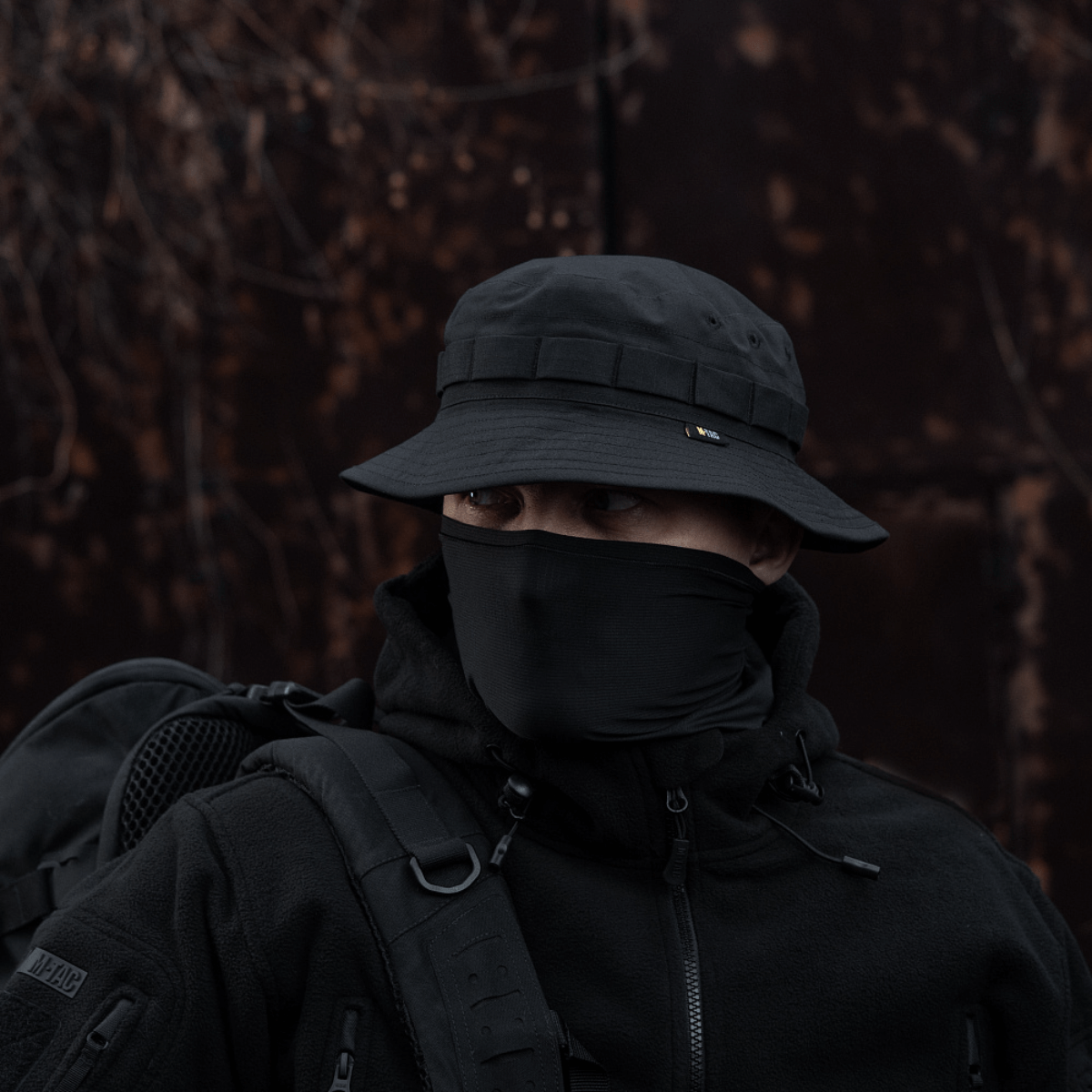 Person iført M-Tac Panama Rip-Stop army-hat i sort med semi-stiv skygge og ventilationshuller, tilpasset til camouflage og beskyttelse mod vind.