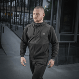 Mand iført M-Tac Pilgrim Bomberjakke, stilfuldt design med hætte, perfekt til hverdagsbrug og sport, den holdbare og komfortable jakke.