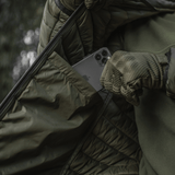 Person placing phone in pocket of M-Tac Stalker Gen.III Jakke, showing nylon fabric and practical design.