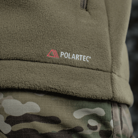 Detalje af M-Tac Combat Fleece Polartec Jakke, viser Polartec®-mærket og camo-bukser, ideel til taktisk og casual brug.