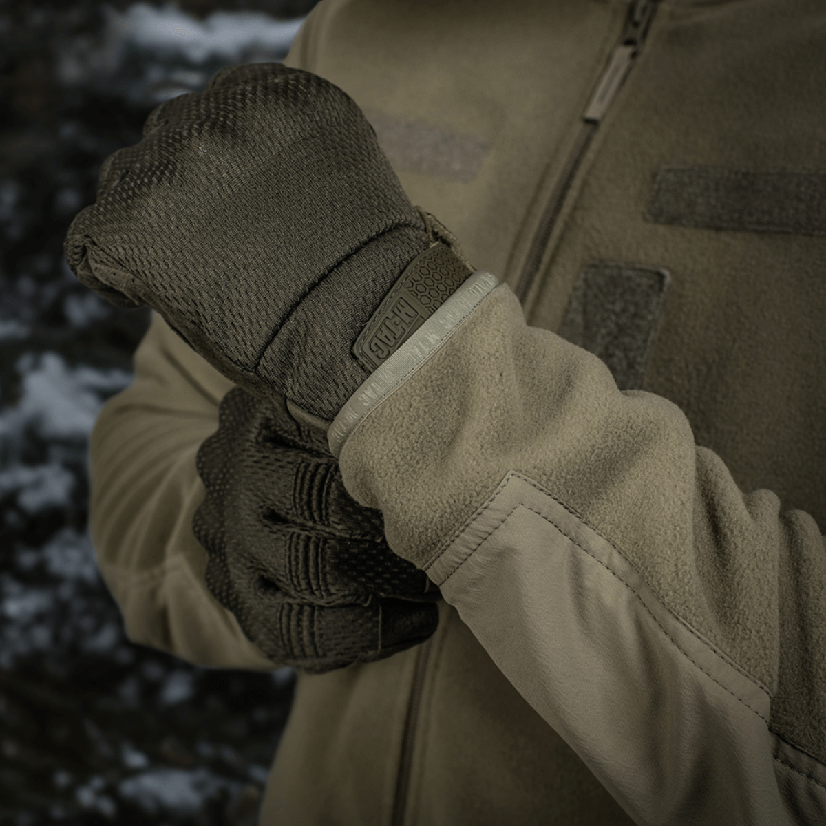 Person iført M-Tac Combat Fleece Polartec Jakke med handsker, fokuserer på taktisk og casual anvendelse i udendørs miljø.
